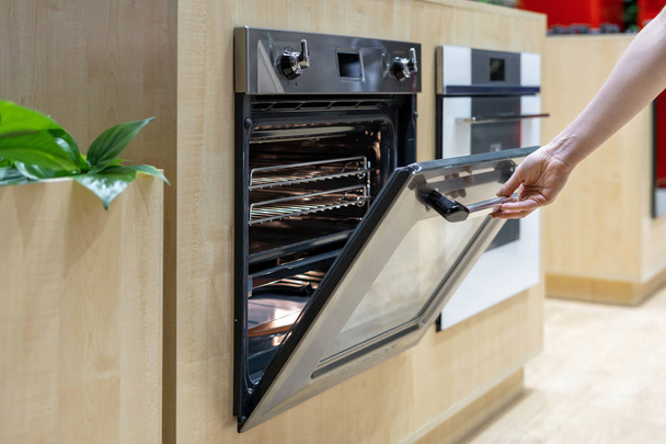 Side view photo of woman hand opening door of new modern built-in oven - Photo, Image