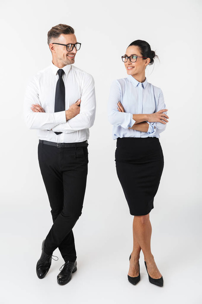Comprimento total de um casal de colegas confiantes vestindo roupas formais em pé isolado sobre fundo branco, braços dobrados
 - Foto, Imagem