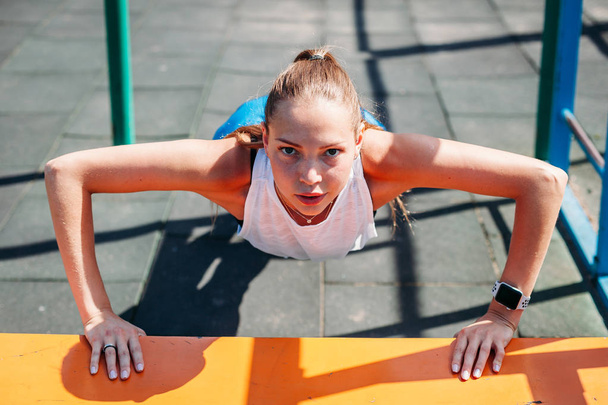 sporty young sexy woman doing push-UPS from bench on sports ground. concept healthy lifestyle - 写真・画像