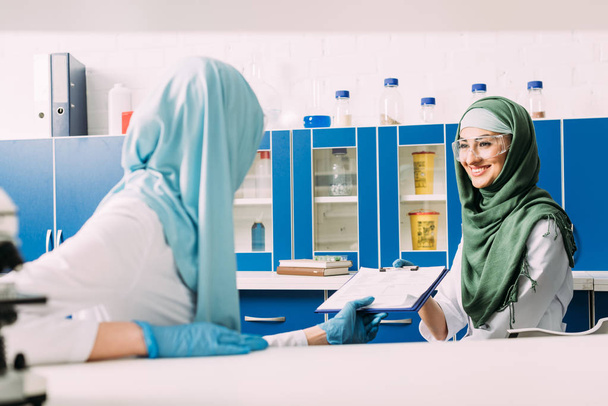 scienziati musulmani femminili in hijab tenendo appunti durante l'esperimento in laboratorio chimico
 - Foto, immagini