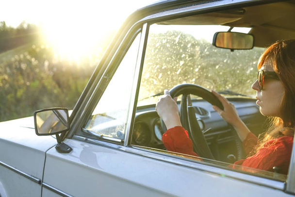 redhead middle age stylish woman driving the white retro aged car. sunny spring day.  - Foto, Imagen