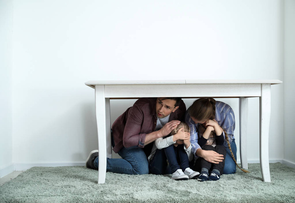 Family under table during earthquake indoors - Photo, Image