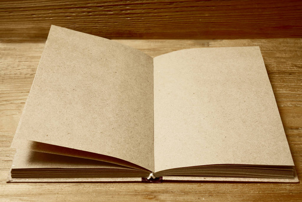 Open brown notebook  on yellow wooden table, top view. empty copy space for inscription.  - Foto, Imagem