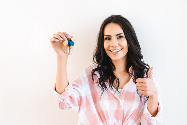 cheerful woman holding key while showing thumb up isolated on white - Φωτογραφία, εικόνα