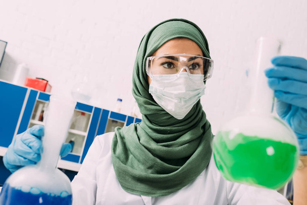Muslimische Wissenschaftlerin hält Fläschchen während Experiment im Chemielabor - Foto, Bild