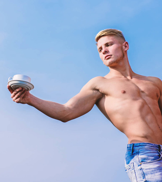 Sexy torso attractive waiter. Man muscular athlete bodybuilder offers you coffee. Waiter bare chest hold coffee cup. Macho muscular chest naked torso hold mug of fresh coffee blue sky background - Foto, afbeelding