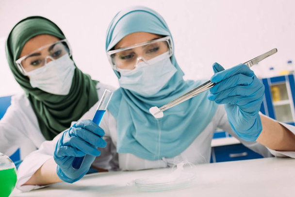 scienziate musulmane che tengono provette, pinzette e ghiaccio secco durante l'esperimento in laboratorio chimico
 - Foto, immagini