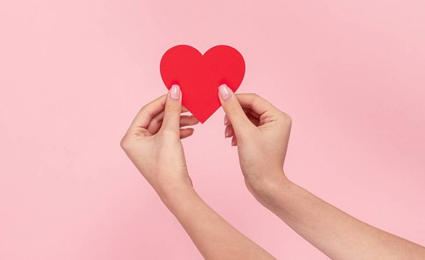 Woman showing red heart on pink background  - Photo, Image