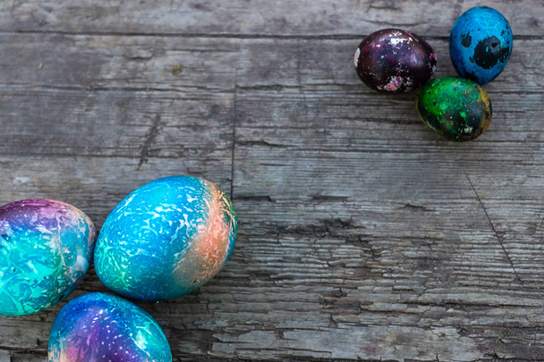 Ovos de Páscoa envoltos em folha colorida em um fundo de madeira, vista superior, espaço de cópia
. - Foto, Imagem