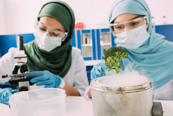 θηλυκό μουσουλμάνων επιστημόνων που πειραματίζεται με μπρόκολο και ξηρό πάγο σε χημικό εργαστήριο - Φωτογραφία, εικόνα