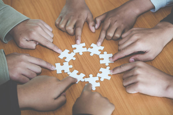 Menschen, die bei der Zusammenstellung von Puzzles helfen, Mitarbeit bei der Entscheidungsfindung, Teamunterstützung bei der Lösung von Problemen und Teamwork-Konzept der Unternehmensgruppe, Nahsicht auf Hände, die Teile verbinden - Foto, Bild