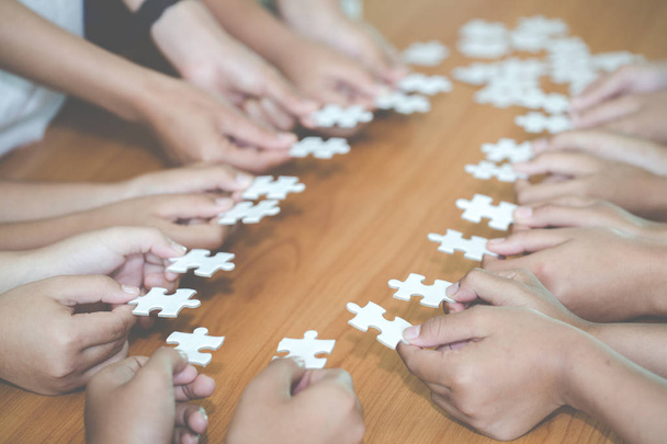 Hände von verschiedenen Leuten, die Puzzleteile zusammensetzen, auf der Suche nach der richtigen Übereinstimmung, Unterstützung bei der Teamarbeit, um ein gemeinsames Lösungskonzept zu finden, Nahsicht von oben - Foto, Bild