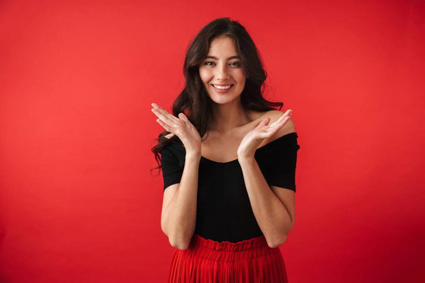 Pretty young woman wearing a dress standing isolated over red background, posing - Foto, Imagem