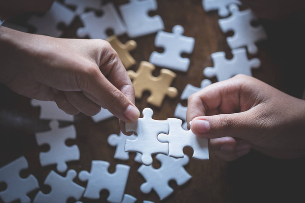 Zwei Frauen versuchen, ein Paar Puzzleteile zu verbinden. Symbol der Verbindung und Verbundenheit. Konzept der Geschäftsstrategie. - Foto, Bild