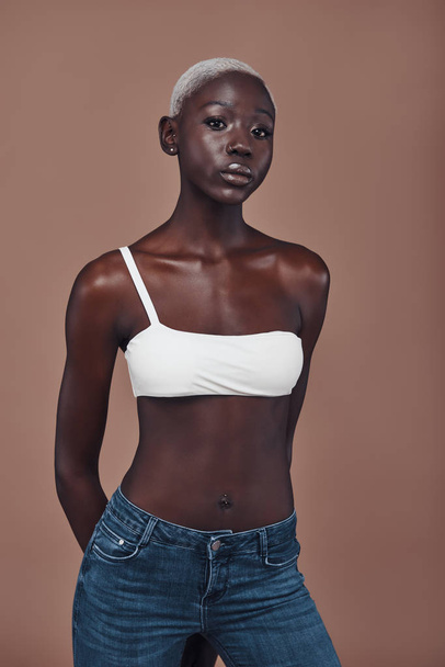 attractive young African woman looking at camera while standing against brown background - Foto, Imagen