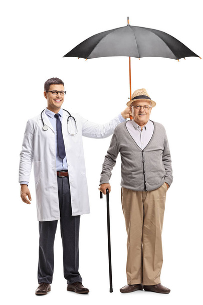 Full length portrait of a young male doctor holding an umbrella over a senior man isolated on white background - Foto, imagen