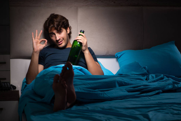 Homem bebendo na cama sob estresse
 - Foto, Imagem