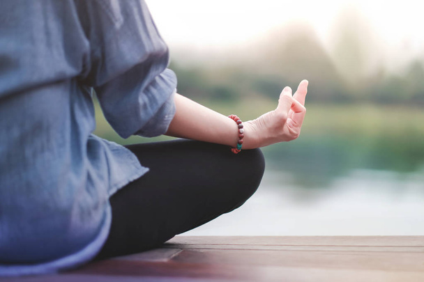 Genç kadın uygulamaları Yoga açık. Lotus pozisyonda oturuyor. Unplugged hayat ve ruh sağlığı kavramı. Sukhasana duruş ve meditasyon - Fotoğraf, Görsel