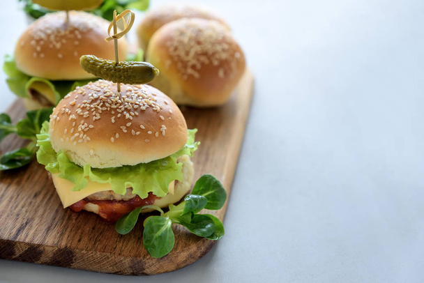 Tasty homemade burgers with lettuce, ketchup, cheese and chicken on gray wooden background. Copy space - Foto, imagen