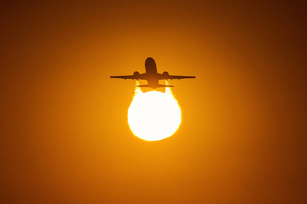Silhouette d'un avion au-dessus du soleil avec de beaux nuages rouges en arrière-plan
 - Photo, image