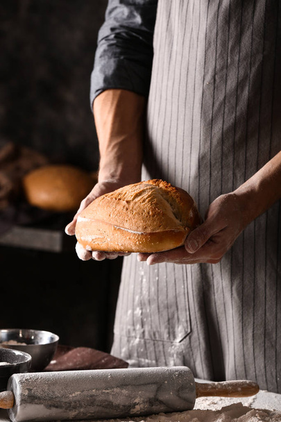 Jeune homme avec du pain fraîchement cuit dans la cuisine
 - Photo, image