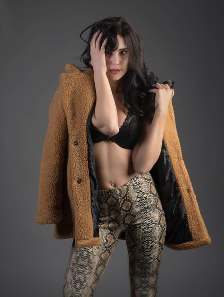 Young beautifl girl brunette with bra and jacket on grey background - Fotó, kép