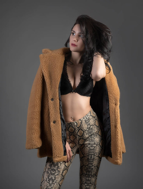 Fiatal beautifl lány barna melltartóját és a kabát szürke háttér - Fotó, kép