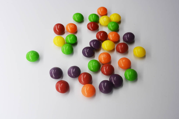 Popularne pyszne słodkie kolorowe jest na białym tle. Dużo słodyczy, okrągłe są w postaci tabletek jasne, więc spocony i tętniącego życiem z jasnych kolorach. - Zdjęcie, obraz