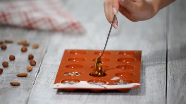 A woman puts in the silicone mold a caramel and nuts filling. - Footage, Video