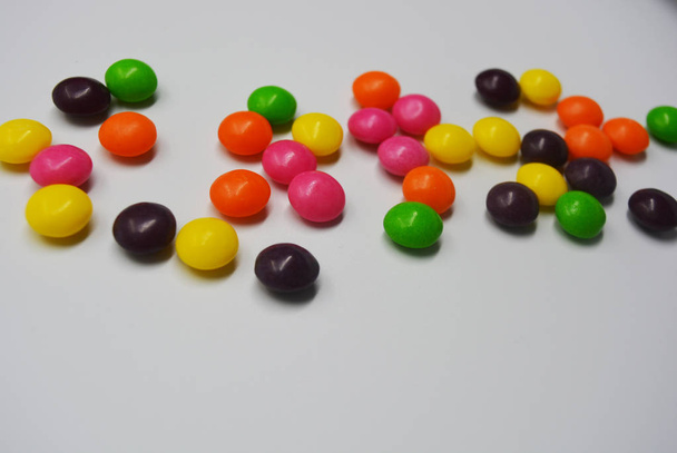 Popular delicioso doce colorido está no fundo branco. Um monte de doces redondos estão na forma de comprimidos brilhantes, tão suados e animados com cores brilhantes
. - Foto, Imagem