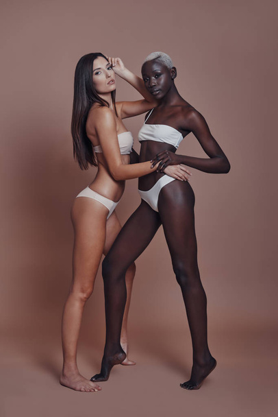 two women models posing in lingerie against brown background - Photo, Image