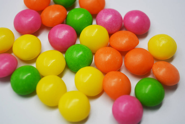 Популярний смачний барвистий солодкий на білому тлі. Багато круглих цукерок у формі яскравих таблеток, тому спітнілі і живі з яскравими кольорами.
. - Фото, зображення