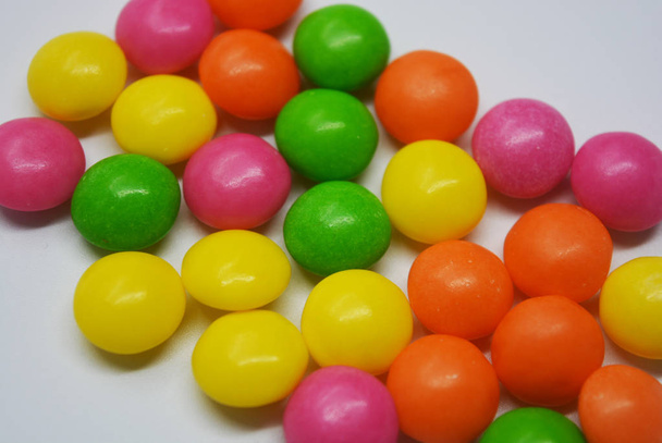 Popular delicioso dulce colorido está sobre fondo blanco. Una gran cantidad de dulces redondos son en forma de tabletas brillantes, tan sudorosas y animadas con colores brillantes
. - Foto, Imagen