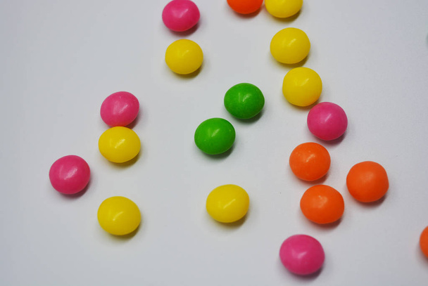 Népszerű, finom, színes édes fehér háttér van. Egy csomó kerek édesség van világos tabletta, így izzadt és élénk, élénk színekkel formájában. - Fotó, kép
