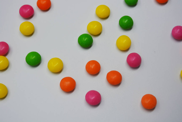 Popularne pyszne słodkie kolorowe jest na białym tle. Dużo słodyczy, okrągłe są w postaci tabletek jasne, więc spocony i tętniącego życiem z jasnych kolorach. - Zdjęcie, obraz