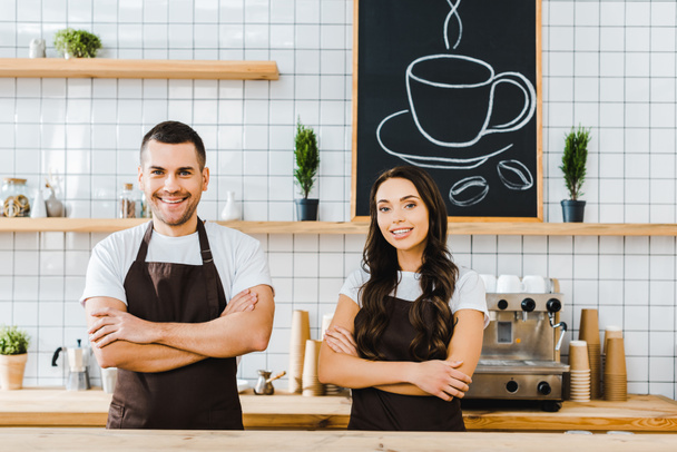 cashiers standing behind wooden bar counter and smiling in coffee house - Photo, Image