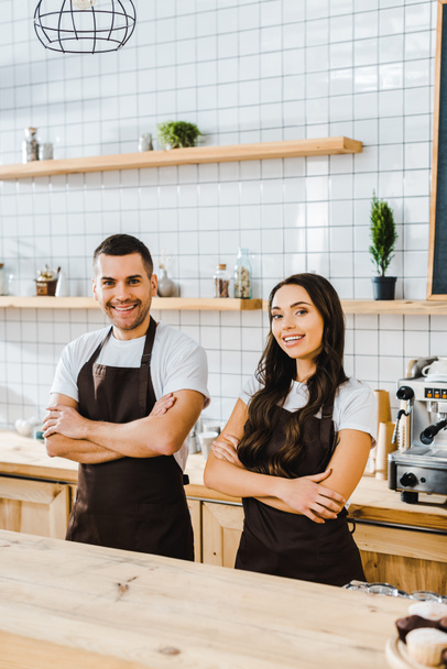 cashiers smiling and standing behind wooden bar counter in coffee house - Photo, Image