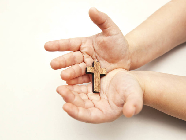 Ένα μικρό ξύλινο σταυρό στα χέρια του παιδιού - Φωτογραφία, εικόνα
