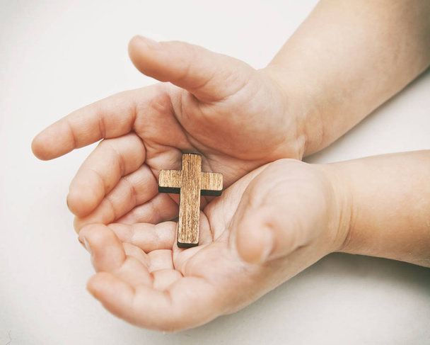 A little wooden cross in the child's hands - Zdjęcie, obraz