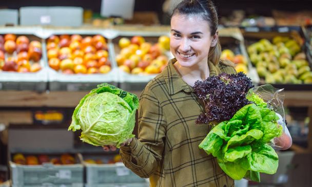 Mujer en el supermercado. Hermosa joven comprando en un supermercado y comprando verduras orgánicas frescas. El concepto de alimentación saludable. Cosecha
 - Foto, imagen