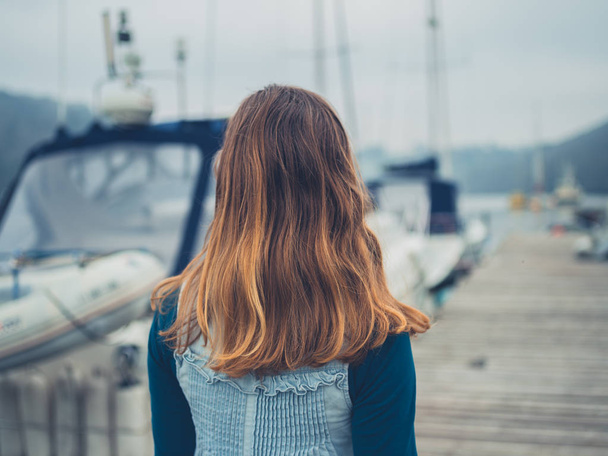 A young woman is walking around in a marina with boats - Foto, imagen