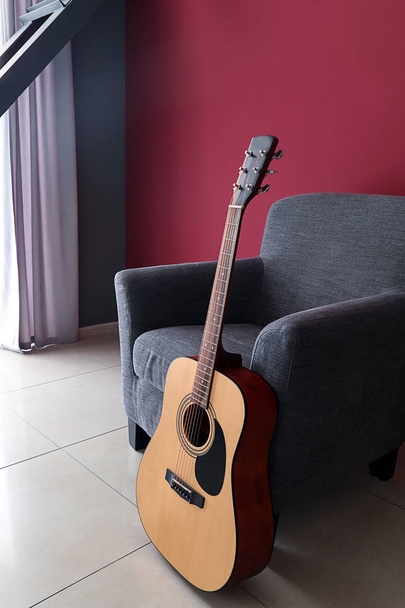 Soft armchair with guitar near color wall in room - Fotoğraf, Görsel