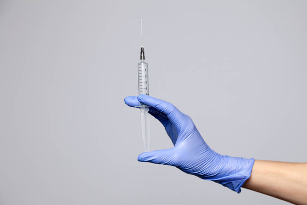 Closeup doctor's hand in rubber latex purple glove hold transparent syringe. Isolated on white background. Concept rejection of vaccinations, injection of HIV, epidemic of AIDS, prevention hepatitis - Foto, Imagem
