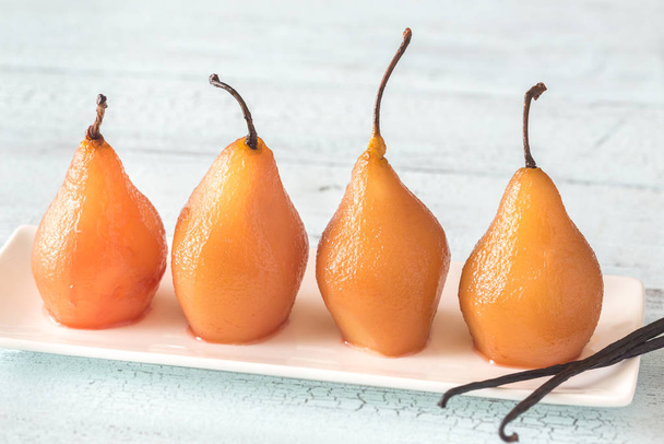 Poached pears in rose wine on the plate - 写真・画像