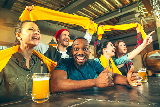 Sport, people, leisure, friendship and entertainment concept - happy football fans or male friends drinking beer and celebrating victory at bar or pub - Valokuva, kuva