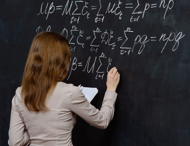 Portret van een mooie student doen wiskunde op een schoolbord - Foto, afbeelding