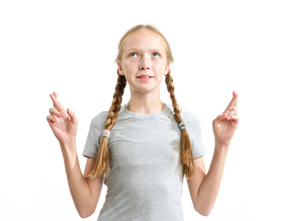 Teen girl crossed her fingers for good luck and made a wish standing on a white background. - Foto, imagen