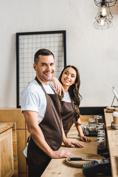 cashiers standing and smiling behind wooden bar counte in coffee house - Foto, Bild