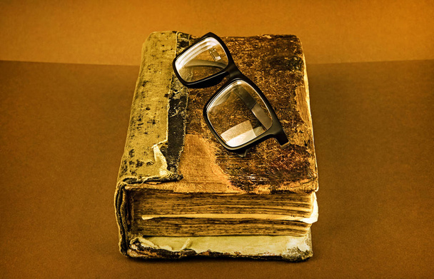 Foto tonica del libro Vintage con un bicchieri sullo sfondo marrone primo piano
 - Foto, immagini