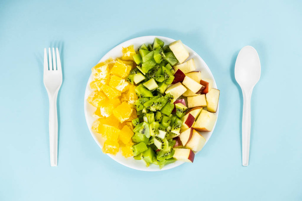 Plant based food diet concept. Top view of fresh fruit on a plate in pale blue background - Valokuva, kuva